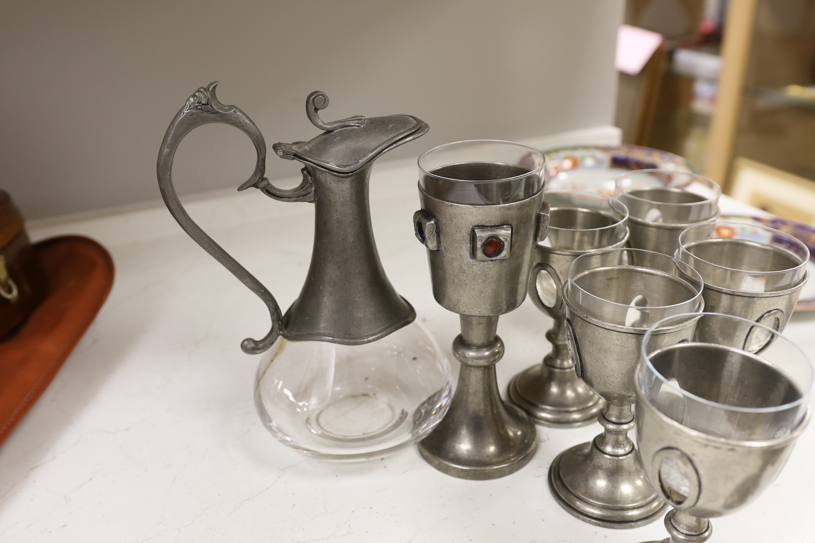 A set of six 20th century French pewter and glass goblets, together with larger example inset with cabochon stones and a pewter mounted glass claret jug, the largest 28cm high
